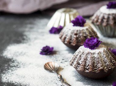 Çikolatalı kek ile pudra şekeri mor çiçekler seçici odak. Karanlık.