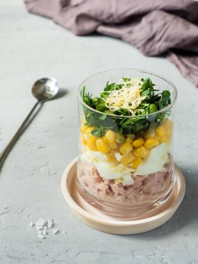 Yumurta Mısır yeşillikleri beton bir tabloda bir cam bardak ile taze ton balığı salatası. kopya alanı.