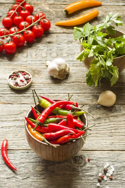 Biber biber ahşap bir kapta baharatlı. Domates Maydanoz sarımsak ahşap rustik zemin üzerine.