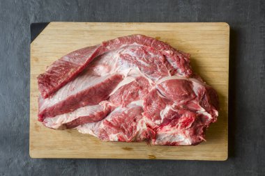 Ahşap kesme tahtası koyu arka plan üzerinde kırmızı ham sığır et parçası.