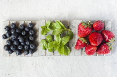 Taze çilek çilek yaban mersini nane kopya alanı metin için bir ahşap stand, gri zemin üzerine.