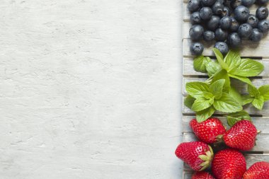 Taze çilek çilek yaban mersini nane kopya alanı metin için bir ahşap stand, gri zemin üzerine.