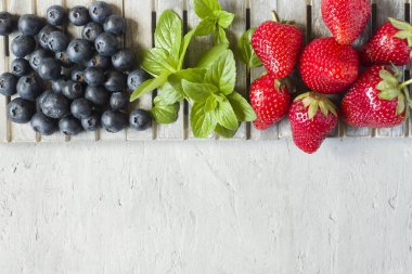 Taze çilek çilek yaban mersini nane kopya alanı metin için bir ahşap stand, gri zemin üzerine.