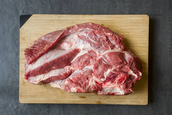 Ahşap kesme tahtası koyu arka plan üzerinde kırmızı ham sığır et parçası.