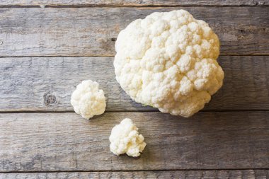 Ahşap arka plan üzerinde parçalar halinde kesilmiş taze organik karnabahar.