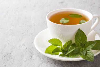 Gri beton zemin üzerine çay ile taze nane yaprakları.