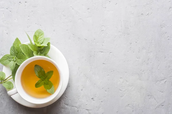 Çay taze nane ile gri beton zemin üzerine bırakır. Kopya alanı