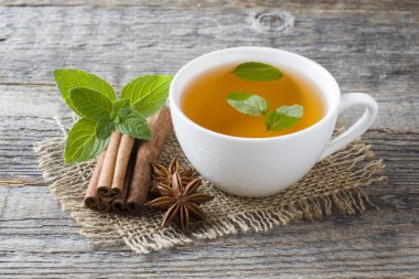 Fincan çay taze nane yaprakları ve bir ahşap zemin üzerine tarçın anason ile. Kopya alanı.