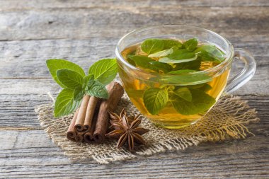 Fincan çay taze nane yaprakları ve bir ahşap zemin üzerine tarçın anason ile. Kopya alanı.