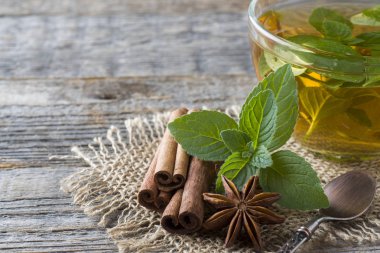 Fincan çay taze nane yaprakları ve bir ahşap zemin üzerine tarçın anason ile. Kopya alanı.