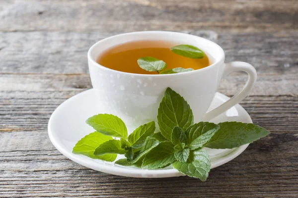 Çay taze nane ile ahşap arka plan üzerinde bırakır. Kopya alanı.