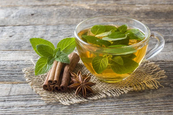 Fincan çay taze nane yaprakları ve bir ahşap zemin üzerine tarçın anason ile. Kopya alanı.