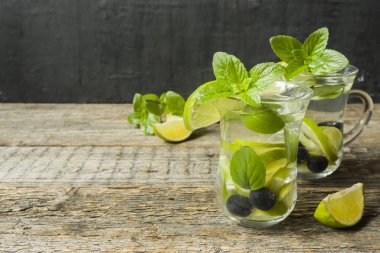 Serinletici içecekler limonata yaz ya da kireç taze nane yaban mersini buzla kokteyl Mojito. Ahşap arka plan.