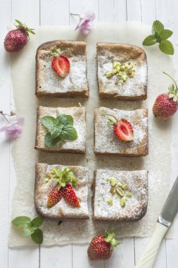 Çilek ile süzme peynir güveç kısmında ve nane, Antep fıstığı hafif bir arka plan üzerinde. Kahvaltı kavramı.