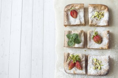 Çilek ile süzme peynir güveç kısmında ve nane, Antep fıstığı hafif bir arka plan üzerinde. Kahvaltı kavramı.