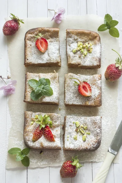 Çilek ile süzme peynir güveç kısmında ve nane, Antep fıstığı hafif bir arka plan üzerinde. Kahvaltı kavramı.