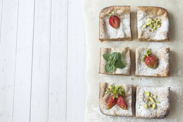 Çilek ile süzme peynir güveç kısmında ve nane, Antep fıstığı hafif bir arka plan üzerinde. Kahvaltı kavramı.