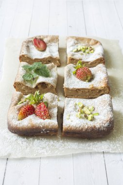 Çilek ile süzme peynir güveç kısmında ve nane, Antep fıstığı hafif bir arka plan üzerinde. Kahvaltı kavramı.