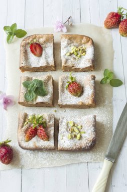 Çilek ile süzme peynir güveç kısmında ve nane, Antep fıstığı hafif bir arka plan üzerinde. Kahvaltı kavramı.