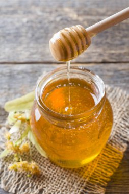 Cam kavanoz bal, ıhlamur çiçek ahşap arka plan üzerinde.