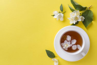 Fincan çay yaprakları parlak sarı bir arka plan üzerinde Yasemin çiçek. Kopya alanı,