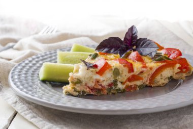 Beyaz ahşap bir masa üzerinde bir tabakta sebze ile hizmet veren omlet.