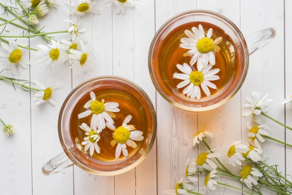 Ahşap arka plan üzerinde çay ve papatya çiçek fincan.