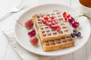 Bir plaka üzerinde yaz meyveleri ile ev yapımı gözleme. Bir fincan çay üzerinde masa lambası. Seçici odak.