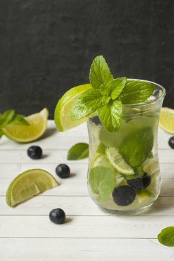 Serinletici içecekler limonata yaz ya da kireç taze nane yaban mersini buzla kokteyl Mojito. Masa lambası, karanlık duvar.