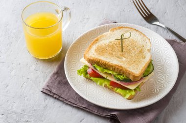 Peynir, jambon ve bir plaka üzerinde taze sebze ile sandviç. Taze meyve suyu ve bir fincan kahve. Kahvaltı kavramı