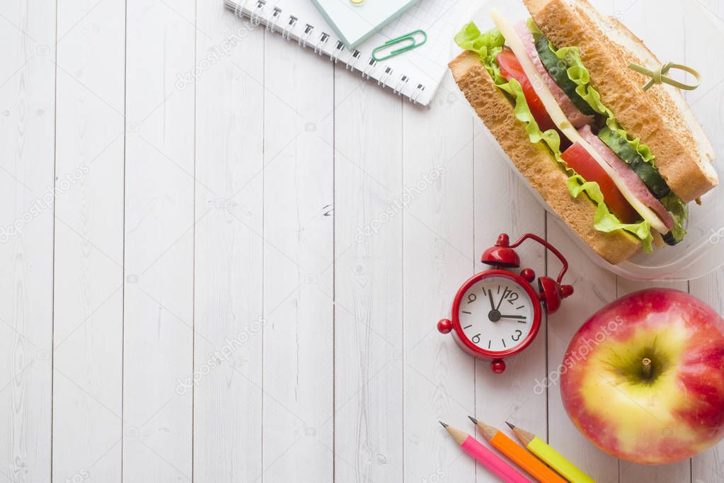 Snack for school with sandwich, fresh Apple and orange juice. Colorful school supplies. Copy space