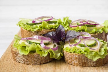 Peynir, salatalık ve soğan kepekli ekmek üzerinde açık sandviçler. Seçici odak