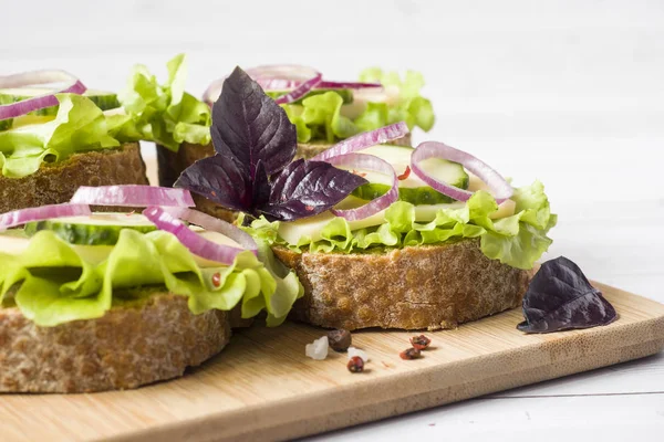Peynir, salatalık ve soğan kepekli ekmek üzerinde açık sandviçler. Seçici odak