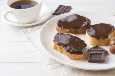 Çikolatalı fındık sandviçle plaka üzerinde yayılmış. Kahve tablo