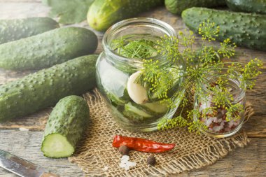 Salatalık turşusu, sarımsak ve baharat için ahşap bir masa üzerinde bir kavanoza dekapaj