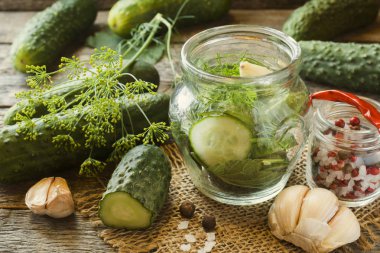 Salatalık turşusu, sarımsak ve baharat için ahşap bir masa üzerinde bir kavanoza dekapaj