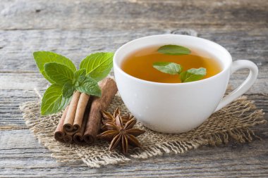 Fincan çay taze nane yaprakları ve bir ahşap zemin üzerine tarçın anason ile. Kopya alanı