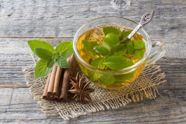 Fincan çay taze nane yaprakları ve bir ahşap zemin üzerine tarçın anason ile. Kopya alanı