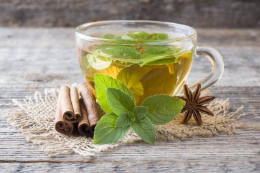 Fincan çay taze nane yaprakları ve bir ahşap zemin üzerine tarçın anason ile. Kopya alanı