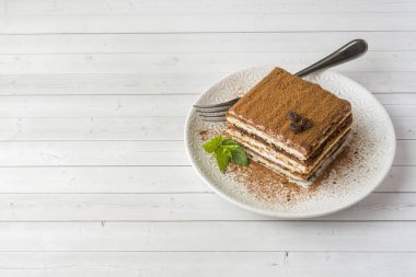 Kahve çekirdekleri ve açık renkli bir tabağa üzerinde taze nane ile leziz Tiramisu pasta.