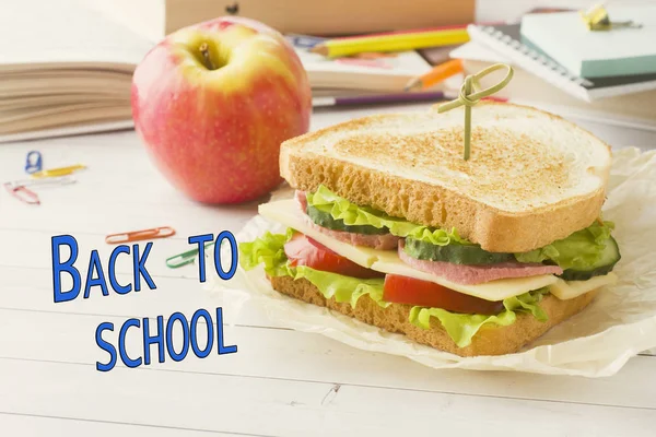 School lunch, a sandwich and an Apple. Books and stationery. Sign back to school