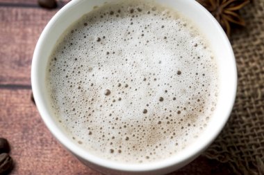 Kahve Kupası ve fincan tabağı süt köpüğü ve şeker kamışı tarçın anason kahve çekirdekleri ile beyaz.