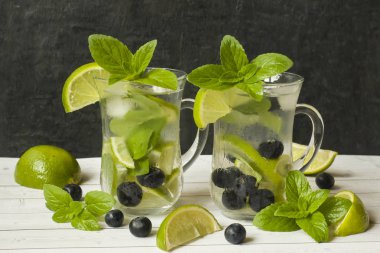 Serinletici içecekler limonata yaz ya da kireç taze nane yaban mersini buzla kokteyl Mojito. Masa lambası, karanlık duvar