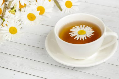 Beyaz ahşap bir masa üzerinde papatya çayı fincan. Kopya alanı