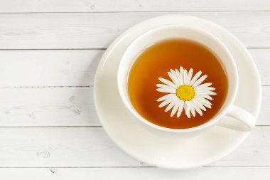 Beyaz ahşap bir masa üzerinde papatya çayı fincan. Kopya alanı