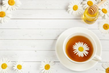 Beyaz ahşap bir masa üzerinde papatya çayı fincan. Kopya alanı
