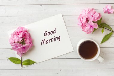 Bir fincan kahve beyaz bir tablo ve pembe Phlox çiçekler. Sabah kahvaltı kavramı