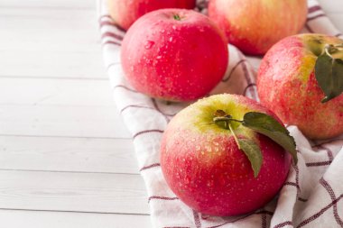 Peçeteye yeşil yaprakları ile taze kırmızı elma. Hafif ahşap arka plan. Metin için boş alan