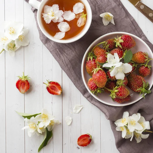 Fresh strawberries and tea with Jasmine flowers on a light background. Summer concept.