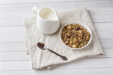 Kahvaltı yulaf gevreği, granül ve Kuruyemiş kuru. Bir tabak ve süt kabı yoğurtlu müsli